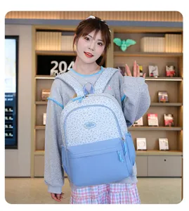 Vista detallada de una mochila escolar con estampado de leopardo azul claro usada por un modelo.