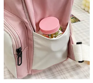 Primo piano sul dettaglio della tasca laterale dello zaino rosa e bianco con zip.