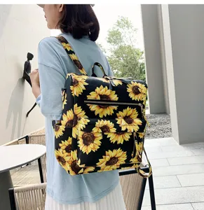 Dettaglio di uno zaino nero con stampa di girasoli indossato da una modella all'aperto.