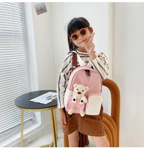 Dettaglio scena zaino rosa per bambini con grazioso orsacchiotto di peluche e ambiente accogliente.