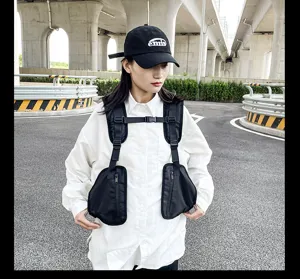 Detailed view of black tactical chest bag and vest worn outdoors by the model.