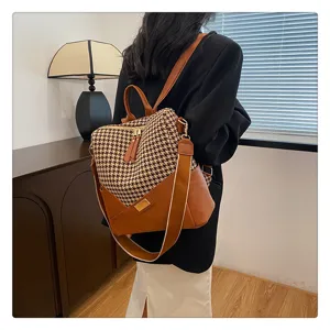 Gedetailleerd overzicht van retro houndstooth rugzak met bruin leer en brede schouderband.
