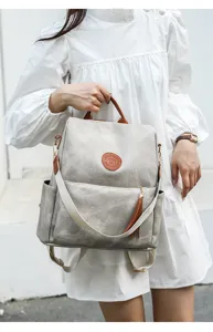 Nahaufnahme Detail des grauen PU Leder Rucksacks mit braunem Griff und hängender Quaste.