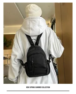 Detailopname van stijlvolle zwarte mini-rugzak gedragen met witte hoodie voor dagelijks.