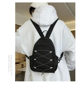 Detailansicht eines schwarzen Nylon-Minirucksacks mit stilvollem Kreuz-Reißverschluss-Design.