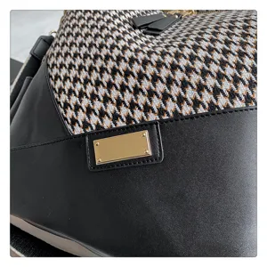 Gedetailleerd overzicht van damesmode houndstooth rugzak met zwart PU-leer en gouden plaataccent.