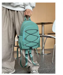 Detailansicht des grünen Nylon-Mini-Rucksacks mit schwarzen Gummizügen im Café.