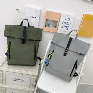 Detailed view of casual roll-top backpacks in green and grey with secure front buckle straps.