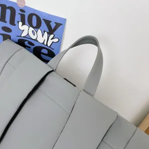 Grey minimalist casual backpack top handle detail, durable fabric construction ideal for daily use.