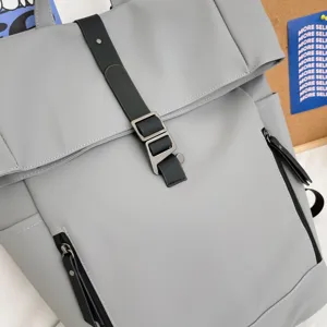 Close-up of grey roll-top casual backpack with black strap and metal buckle detail.