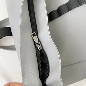 Close-up detail of grey waterproof backpack fabric, smooth black zipper and metal pull.