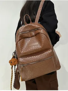 Brauner geflochtener PU-Leder Rucksack Detailansicht mit Textur und süßem Bärenanhänger.