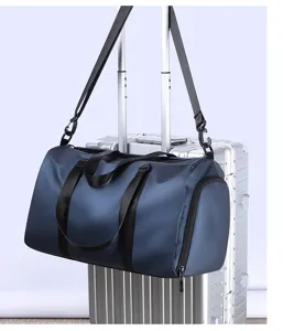 Vue détaillée d'un grand sac de voyage suspendu à la poignée de valise avec sangles.