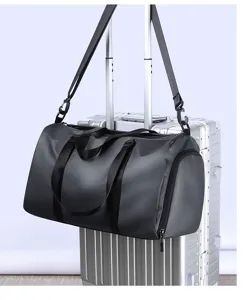 Grand sac de voyage sport noir elegant suspendu a la poignee de valise vue detaillee.