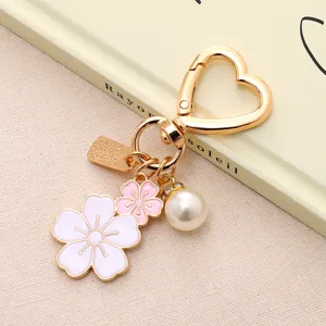 Portachiavi a cuore dorato con pendenti a fiori di ciliegio rosa e ciondolo a perla elegante
