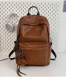 Nahaufnahme des retro braunen PU-Leder-Rucksacks mit Vordertasche und süßem Bärenanhänger.