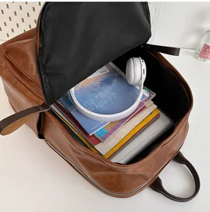 Detailansicht des offenen braunen PU-Leder-Rucksacks mit geräumigem Innenraum voller Bücher.