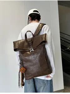 Brown PU leather roll top backpack detail view, vintage travel bag on model showing style.