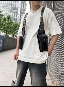 Detail shot of black PU leather tactical vest bag worn over white tee in urban street style.