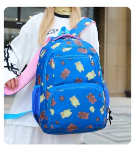 Détail du sac à dos bleu avec motif d'ours, bretelles roses et poches pratiques pour l'école.