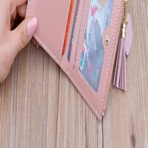 Portafoglio corto rosa da donna con cerniera e nappa, dotato di comodi scomparti per carte.