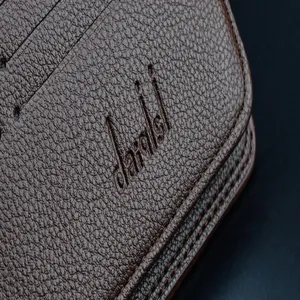 Detailaufnahme der braunen Lichi-Muster Herren Geldbörse Textur und geprägtes Logo.