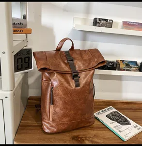 Lifestyle detailweergave van bruine PU lederen roll-top rugzak met gesp en voorste vak.
