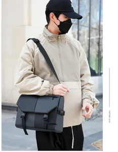 Detailed view of the black waterproof oxford crossbody messenger bag worn by male model.