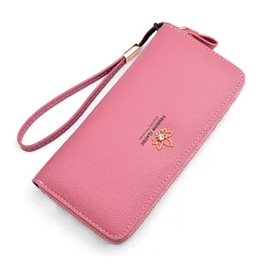 Women's long zipper wallet pink PU leather clutch with wrist strap and leaf charm.