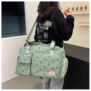 Close-up detail of the cute strawberry corduroy travel duffel bag, showing pockets and sturdy straps.