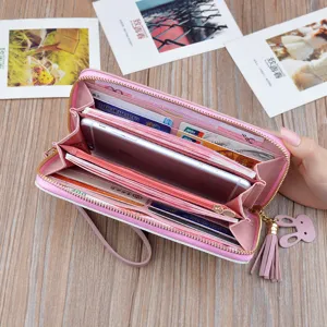 Women long zipper wallet pink PU leather clutch bag with tassel and phone slot inside.