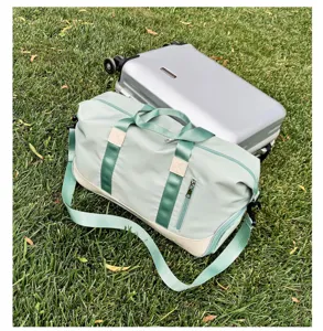 Vista detallada de la bolsa de viaje verde menta con correa sobre césped exterior.