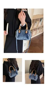 Detailed view of vintage washed denim boston handbag with brown leather handles and strap.