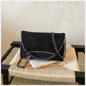 Bolso cruzado tipo sobre de ante sintético negro con detalles de cadena y diseño elegante.