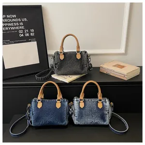 Washed denim Boston handbag detail showing texture, contrast leather handles and strap.