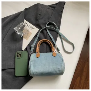 Detailed view of casual vintage denim boston handbag with brown handles and strap.