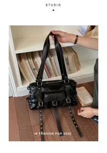 Punk style black leather tote bag with multiple belt straps and metal eyelet details for women.