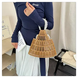 Vista dettagliata della borsa a mano in bambù intrecciato a mano con elegante manico di perle.