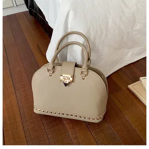Elegante beige koepel handtas met gouden hardware en stijlvolle studs voor vrouwen.