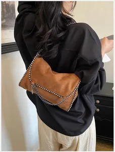 Detalle de bolso bandolera de ante marrón, elegante bolso cruzado con cadena de moda.