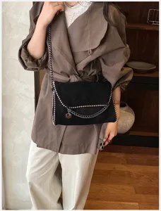 Vista detallada del bolso cruzado de ante negro con cadena para un estilo moderno y elegante.