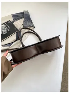 Detailed view of the brown unique shaped handbag, premium PU leather niche commuter underarm bag.