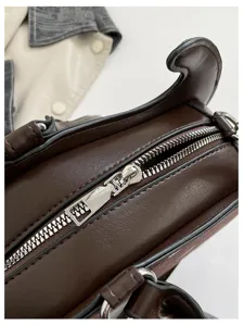 Close-up detail of brown irregular handbag zipper and hardware, unique niche design style.