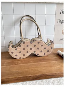 Detail view of quirky mustache shaped handbag with polka dots pattern on wooden surface