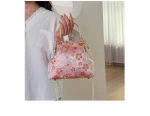 Close-upweergave van de roze geborduurde handtas met bloemen en elegante parelkettingriem.