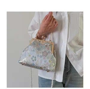 Elegante bloem geborduurde beugel schelp handtas met metalen frame en parel schouderband.