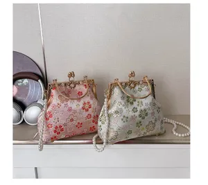 Gedetailleerd overzicht van vintage geborduurde bloemen handtas met parelketting.