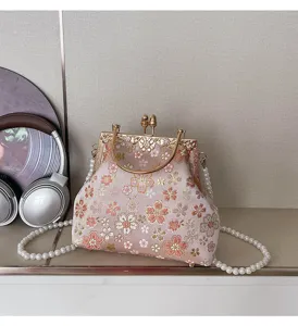 Gedetailleerde close-up van roze geborduurde bloemen tas met parels en metalen handvat.