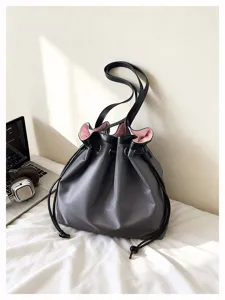 Detailaufnahme der grauen Nylontasche mit pinkem Innenfutter und elegantem Kordelzug.
