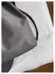 Detailaufnahme einer grauen Nylontasche mit glattem Stoff und feinem Schultergurt.